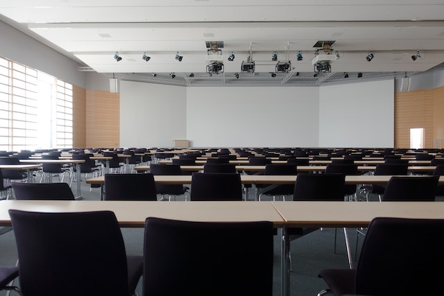 An empty classroom with a large screen at the front of the room.