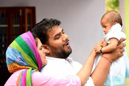 Mother and father are holding their child in the air.